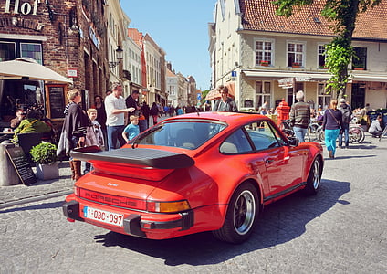 red Porsche 911 parked on road near people and buildings thumbnail