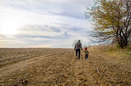 man and boy walking on dirt road near brown tree thumbnail