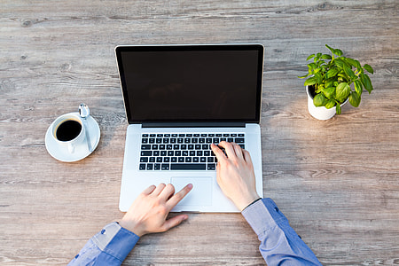 person wearing blue long-sleeved dress shirt near silver MacBook thumbnail