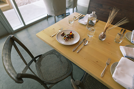 round white plate beside knife, spoon, and fork on brown wooden table thumbnail