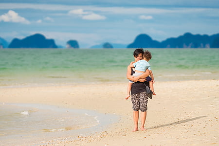 woman carrying baby on sea shore thumbnail