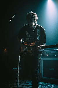 man playing black electric guitar on stage thumbnail