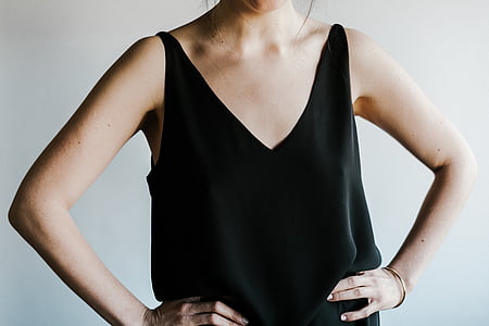 woman wearing black tank top standing near white wall thumbnail