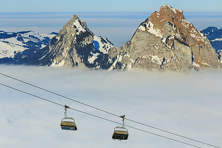 two brown cable cart above on white clouds near mountain at daytime thumbnail