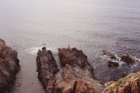 person standing on brown rock formations thumbnail