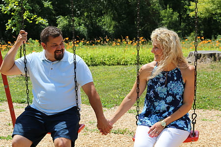 couple sitting on outdoor swing while holding hands thumbnail
