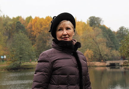 man wearing black fur coat with hat beside body of water at daytime thumbnail