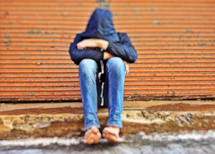 person wearing hoodie sitting near brown background thumbnail