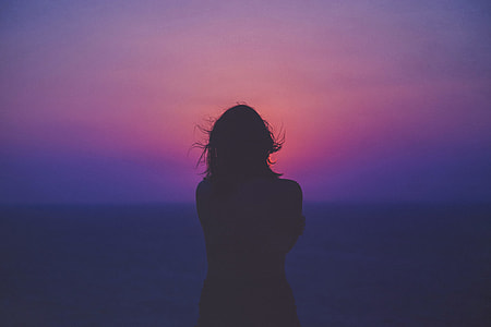 photo of silhouette of woman standing near beach thumbnail