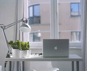 silver Macbook beside glasses and gooseneck lamp on table thumbnail