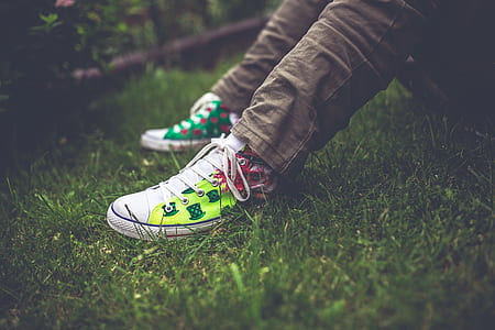 person in brown jeans and pair of white sneakers sitting on grass thumbnail