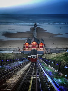 white and red train towards station near body of water thumbnail
