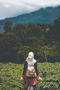 woman walking in bush under cloudy sky during daytime thumbnail