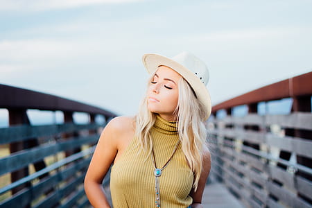 woman wearing brown sleeveless top and white hat thumbnail