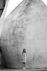 grayscale photography of woman standing beside wall thumbnail