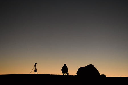 silhouette photography of sitting person beside camping tent thumbnail