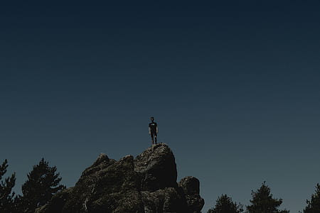 man standing on gray rock thumbnail
