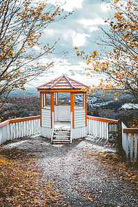 white and orange wooden gazebo on top of hill at daytime thumbnail
