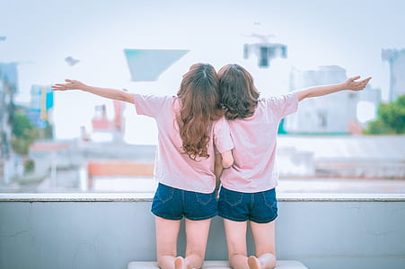 two girl wearing pink top kneeling on white chair thumbnail