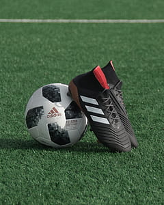 white adidas soccer ball and pair of shoes on green grass field thumbnail