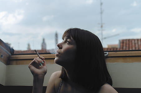 woman puffing cigarette during daytime thumbnail