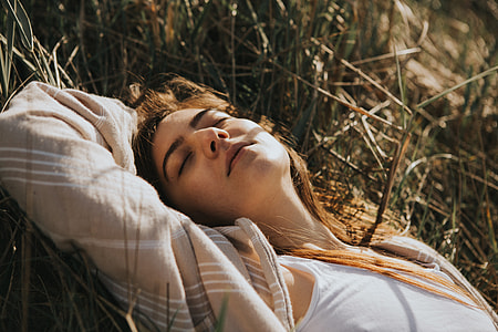 woman wearing brown, white, and gray plaid blazer lying on grass at daytime thumbnail