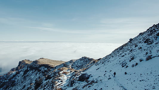 person walking on white and brown mountain thumbnail