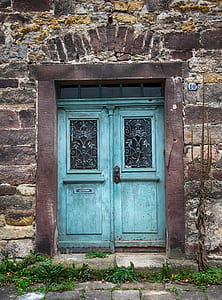 gray and black concrete building with teal wooden doors closed thumbnail