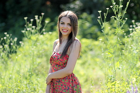 woman wearing red and green dress standing beside green plants thumbnail
