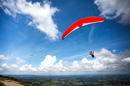 person paragliding under blue cloudy skies thumbnail