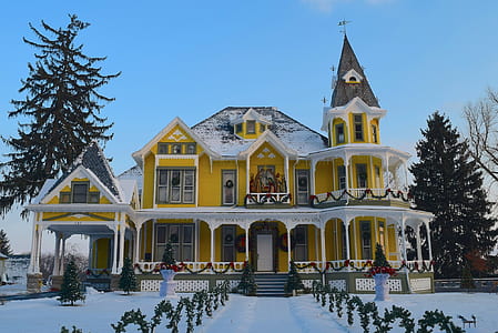 yellow and white concrete house surrounded with pine trees covered with snow under blue sky at daytime thumbnail