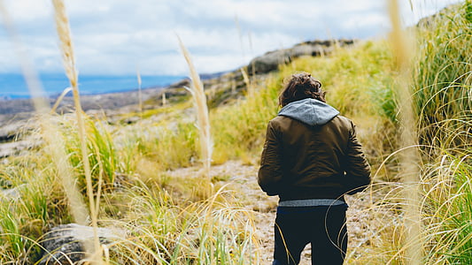 person wearing jacket walking between grass field outdoor thumbnail