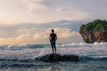 Man Standing on Stone Near Seashore during Sunrise Photography thumbnail