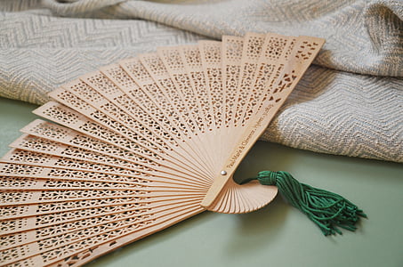 beige hand fan beside beige knitted textile thumbnail