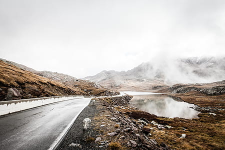 asphalt road beside body of water and mountain at distance thumbnail