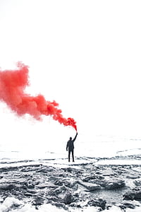 selective photo of a man standing near the shore holding smoking powder thumbnail