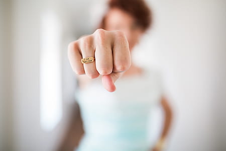 woman wearing white t-shirt showing fist with gold-colored ring selective focus photography thumbnail