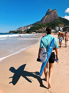 Person In Teal Top And Black Shorts Walking On Seashore thumbnail