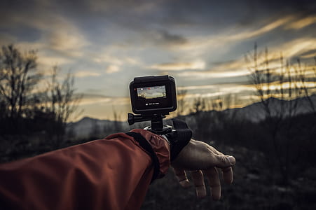 selective focus photo of person taking video using action camera thumbnail