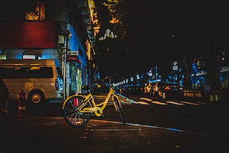 yellow city bike on road way during nighttime thumbnail