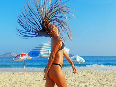 woman flips her hair on white sandy beach during daytime thumbnail