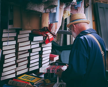 man in black shirt wearing hat holding book during daytime thumbnail