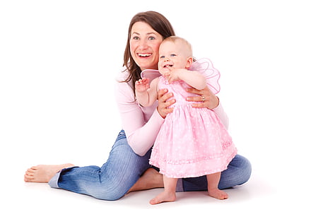 woman in pink long-sleeved top and blue jeans sitting on floor with infant in pink dress thumbnail