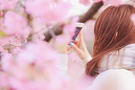 woman wearing white sweater with scarf on neck taking selfie beside tree during daytime thumbnail