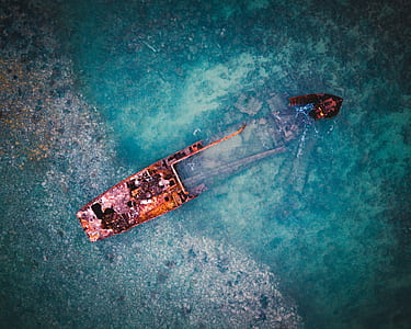 brown and black boat sinking in body of water thumbnail