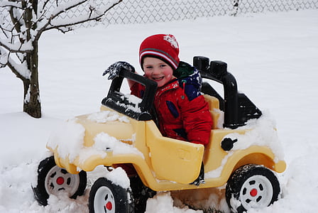 boy riding a yellow vehicle ride-on toy outside with snow thumbnail