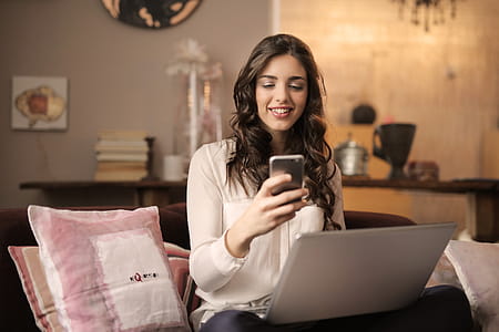 A young woman working on her laptop looks at her mobile phone in the living room thumbnail