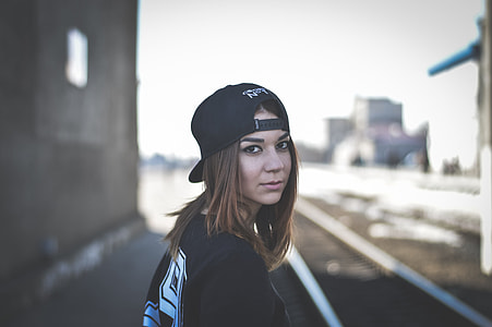 shallow focus photography of woman in black shirt wearing black cap thumbnail
