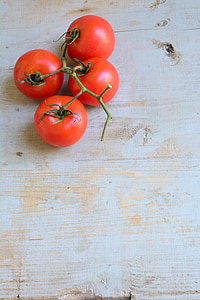 four tomatoes on beige wooden table thumbnail