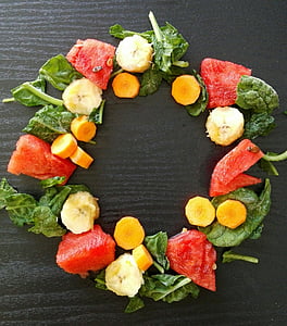 circle formed sliced watermelon, banana, and carrots with green spinach thumbnail